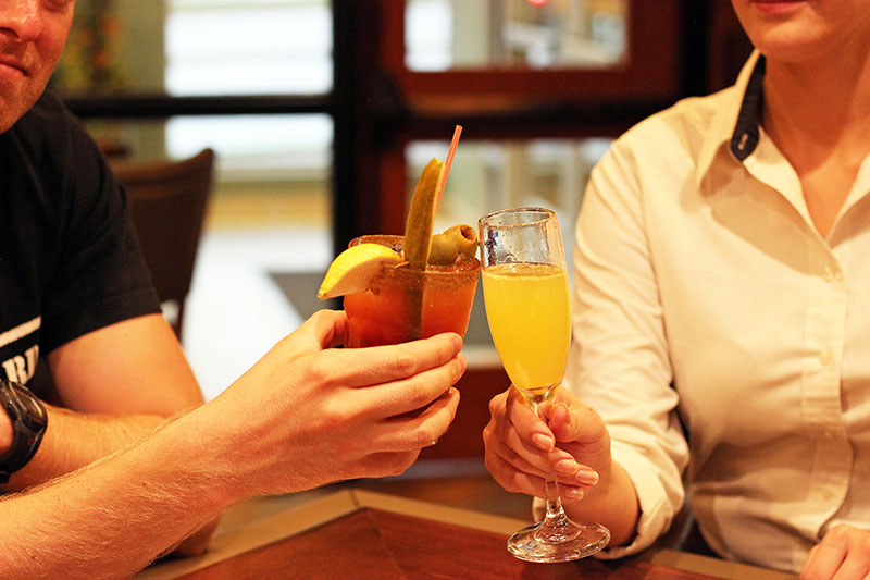man and woman celebrating with a Bloody Mary and Mimosa